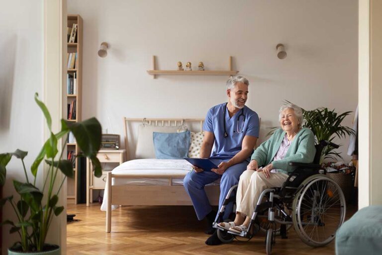 A family member sits with an elderly loved one in a cozy living room, sharing a quiet moment.