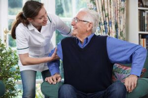 Older adults and children create artwork together around a table in a bright common room.